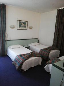 een hotelkamer met 2 bedden in een kamer bij Hôtel de Nevers in Lourdes