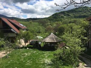 a house with a gazebo in the middle of a field at Pensiune Daniela in Corbeni
