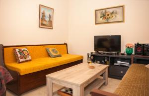 a living room with a yellow couch and a tv at Tranquility House in Livadia