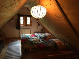 a attic room with a bed and a chandelier at Woodenhouse Maramures in Vişeu de Sus
