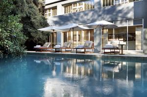 a pool with chairs and umbrellas next to a building at Saxon Hotel, Villas & Spa in Johannesburg