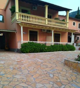 a house with a balcony and a stone patio at Twins Studios in Benitses