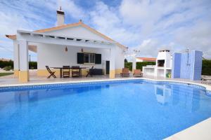 una villa con piscina di fronte a una casa di Casa Luna a Praia da Arrifana