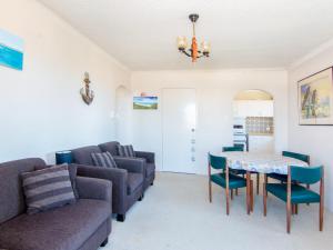 a living room with a couch and a table and chairs at Seabreeze 4 opposite the bowling club Tuncurry in Tuncurry