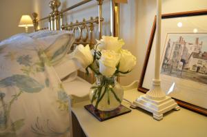 a vase of flowers on a table next to a bed at 19 Upper Linney in Ludlow