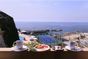 a table with a plate of food and a view of a tennis court at Cimer SafraMarine Beach Resort in Safra