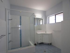 Un baño blanco con ducha y lavabo. en Sandcastle 7 with WiFi, en Tuncurry 4 fotos más