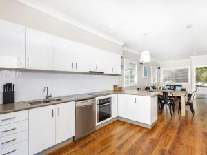 a kitchen with white cabinets and a wooden floor at Sandy Toes in Forster