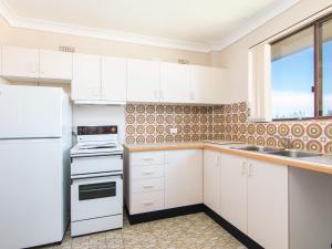 a kitchen with white cabinets and a white refrigerator at Seabreeze 4 Opposite Bowling Club in Tuncurry