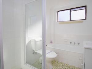 a white bathroom with a toilet and a shower at Seabreeze 6 in Tuncurry