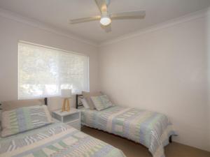 a bedroom with two beds and a ceiling fan at St James 6 in Tuncurry