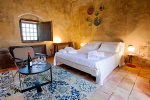 ein Schlafzimmer mit einem weißen Bett und einem Tisch in der Unterkunft Wine Relais Feudi Del Pisciotto in Niscemi