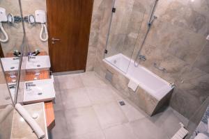 een badkamer met een douche, een bad en een wastafel bij Radon Plaza in Sarajevo