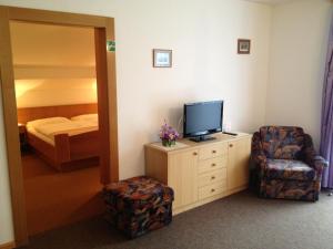 ein Hotelzimmer mit einem TV, einem Stuhl und einem Bett in der Unterkunft Pension & Appartement Fortin in Bad Kleinkirchheim