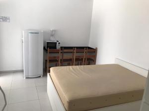 a room with a bed and a table and a refrigerator at Kitnet in Ubatuba