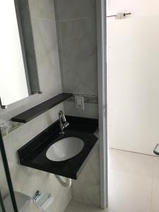 La salle de bains est pourvue d'un lavabo et d'un miroir. dans l'établissement Kitnet, à Ubatuba