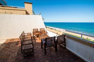 balkon z krzesłami i stołami oraz oceanem w obiekcie Apartamentos Be Suites Primera Linea w mieście Oropesa del Mar