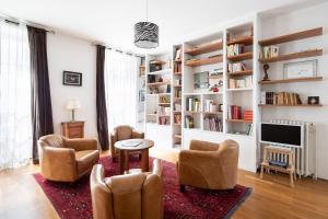 a living room with chairs and a television and bookshelves at L'Esquisse by Cocoonr in Nantes