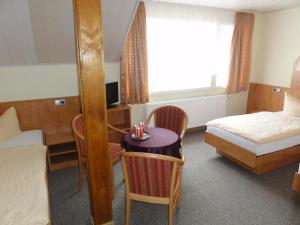 a hotel room with a bed and a table and chairs at Hotel Garni Melchendorf in Erfurt