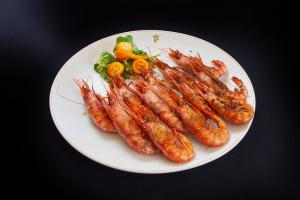 un plato de comida con camarones y verduras en una mesa en Parador de Benicarló, en Benicarló