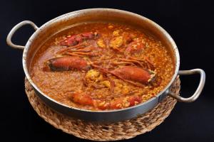 una olla de comida con carne y salsa en Parador de Benicarló, en Benicarló