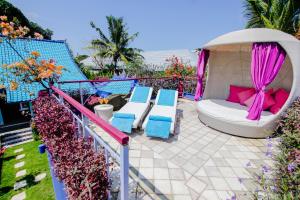 a patio with a bed and chairs on a balcony at Villa Majorelle Bali in Seminyak