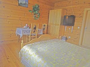 1 dormitorio con cama, mesa y TV en Pas Medžiotoją Motelis en Kryžkalnis
