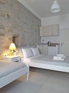 Habitación blanca con 2 camas y cocina en Klironomos Apartments Logaras, en Logaras