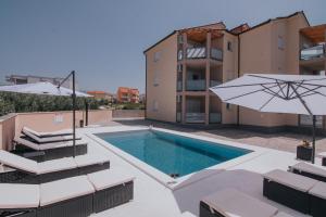 a swimming pool with two chairs and an umbrella at Poolside Hideout Apartments in Novalja