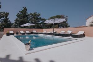 a swimming pool with chairs and umbrellas at Poolside Hideout Apartments in Novalja