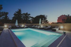 a large swimming pool with chairs and umbrellas at Poolside Hideout Apartments in Novalja