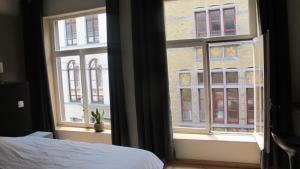 a bedroom with a bed and a window with a building at Huize Maeterlinck in Ghent