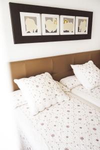 um quarto com uma cama com roupa de cama branca e fotografias na parede em Piso turístico Belisa em Lerma