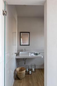 a white bathroom with a sink and a basket at Suites Menaggio in Menaggio