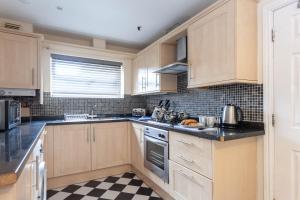 a kitchen with wooden cabinets and a checkered floor at Executive St Marys House in Warrington