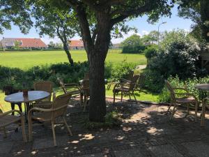 a group of tables and chairs under a tree at Hotel De Horper Wielen in Kaard