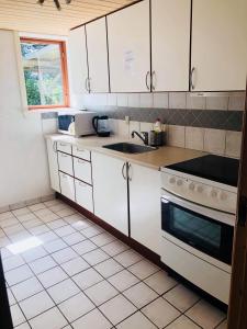 a kitchen with white cabinets and a sink and a stove at Feriestedet Rønne in Billum