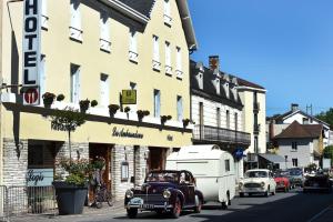 een oude auto die door een straat rijdt voor een gebouw bij Les Ambassadeurs Hotel - Logis in Souillac