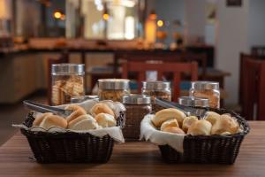 two baskets of bread sitting on a wooden table at Hotel Ciribaí in Maceió