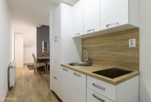 a kitchen with white cabinets and a sink and a table at Apartmani Gundulić in Osijek
