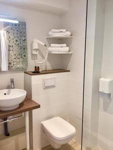 a white bathroom with a toilet and a sink at Hôtel Beau Site in Le Lavandou