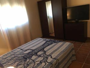 Un dormitorio con una cama y un televisor de pantalla plana. en Casa Baños, en Manilva