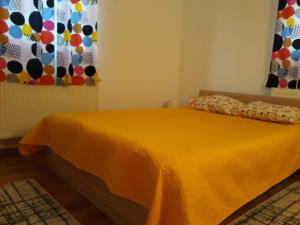 a bed in a room with a yellow blanket at Canadian House in Sărata-Monteoru