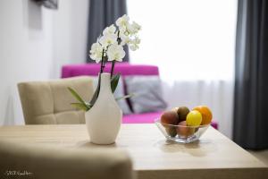 a vase with flowers and a bowl of fruit on a table at Apartmani Gundulić in Osijek +18 photos