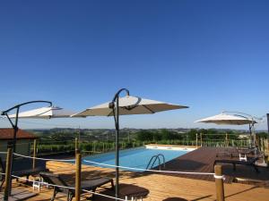 a pool with umbrellas and chairs and a swimming pool at B&B La Gibiana in Costigliole dʼAsti