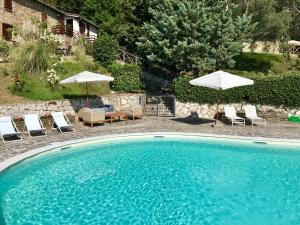 古比奧的住宿－La Panoramica Gubbio - Maison de Charme - Casette e appartamenti self catering per vacanze meravigliose!，一个带椅子和遮阳伞的大型游泳池