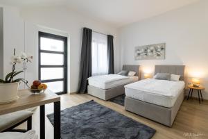 a white room with two beds and a table and a table sidx sidx at Apartmani Gundulić in Osijek