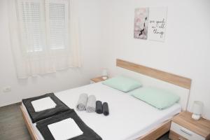 un letto bianco con 2 cuscini e un paio di scarpe di Apartments Mino a Ražanac (Rasanze)