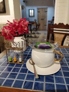 a table with a tea pot and flowers on it at The White Balcao in Panaji