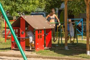 a woman and two children playing on a playground at Camping la Plage Lot Vallée de la Dordogne Rocamadour in Meyronne
